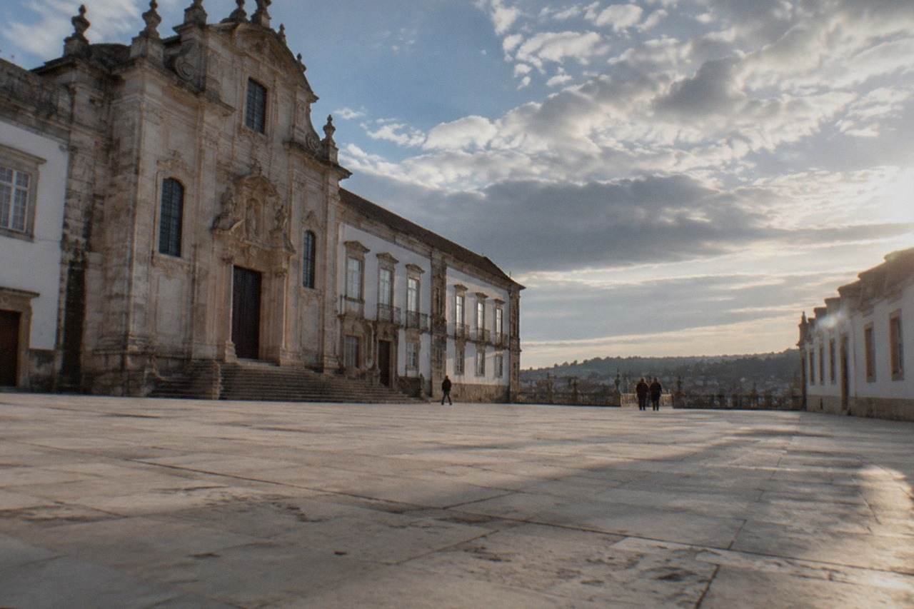 The grand baroque facade and courtyard of the University of Coimbra on a bright day