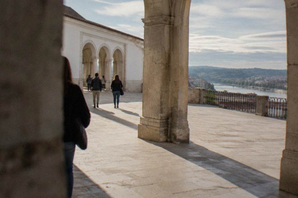 Visitors walking through the stone arches of the Royal Palace at the University of Coimbra