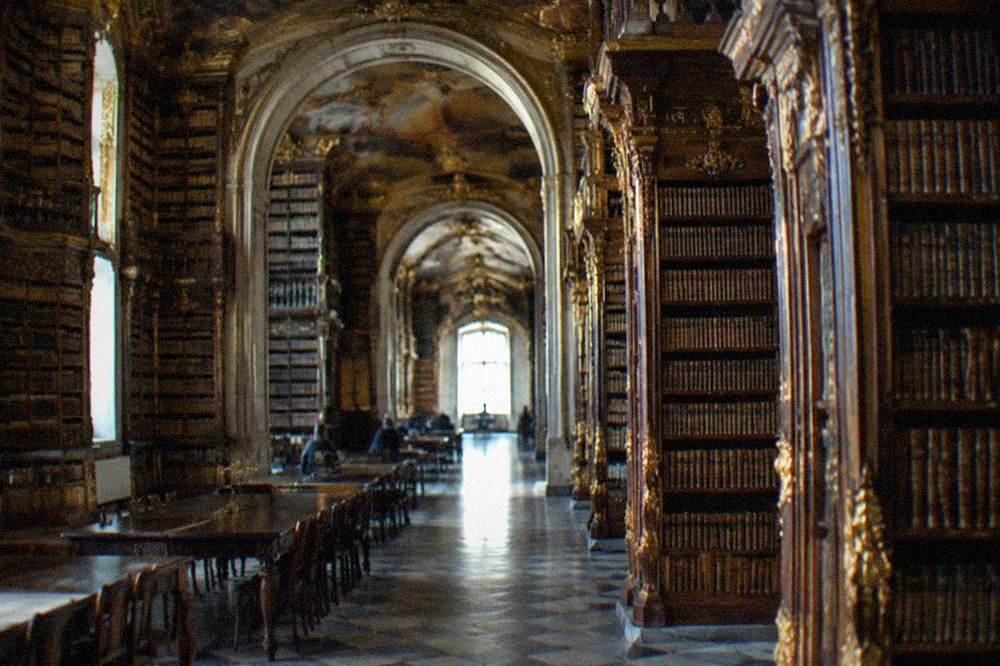 The ornate gilded interior of the Biblioteca Joanina with tall wooden bookshelves