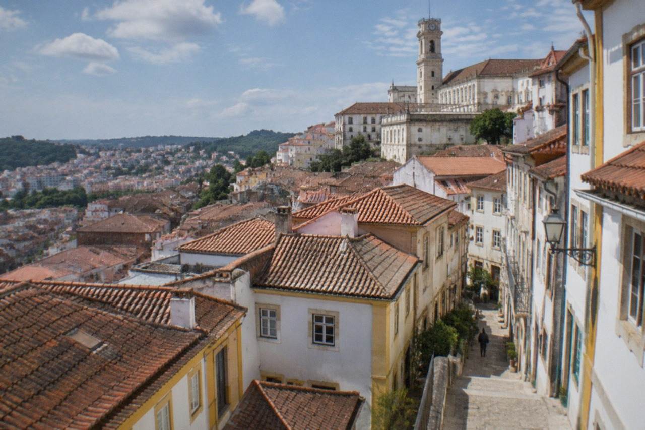 View over Coimbra's old town rooftops toward the University tower under a clear sky