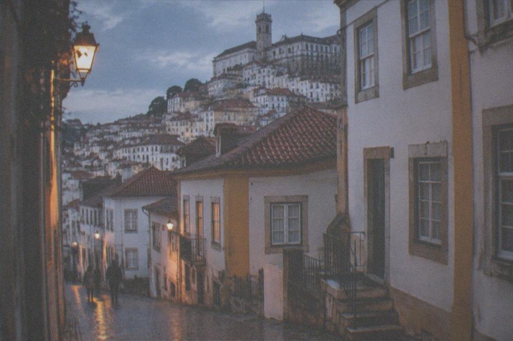 Rain-slicked cobbled street in Coimbra's old town with reflections in the evening light
