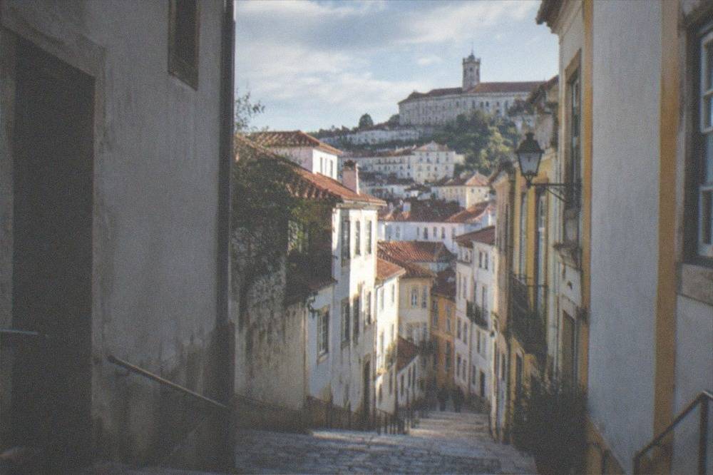 A shaded stone staircase in Coimbra climbing toward the university hill on a bright day