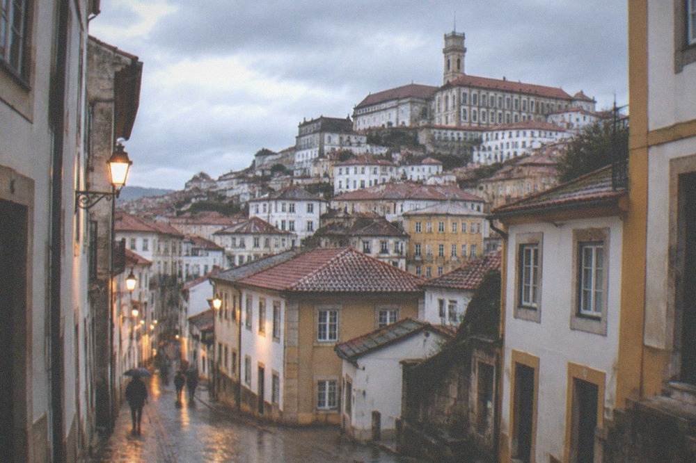Wet cobblestone streets in Coimbra's old town reflecting evening light after rain