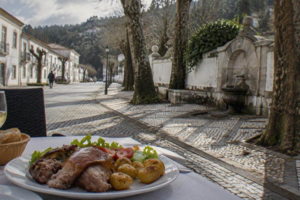 A plate of roasted suckling pig with potatoes and salad on a restaurant table