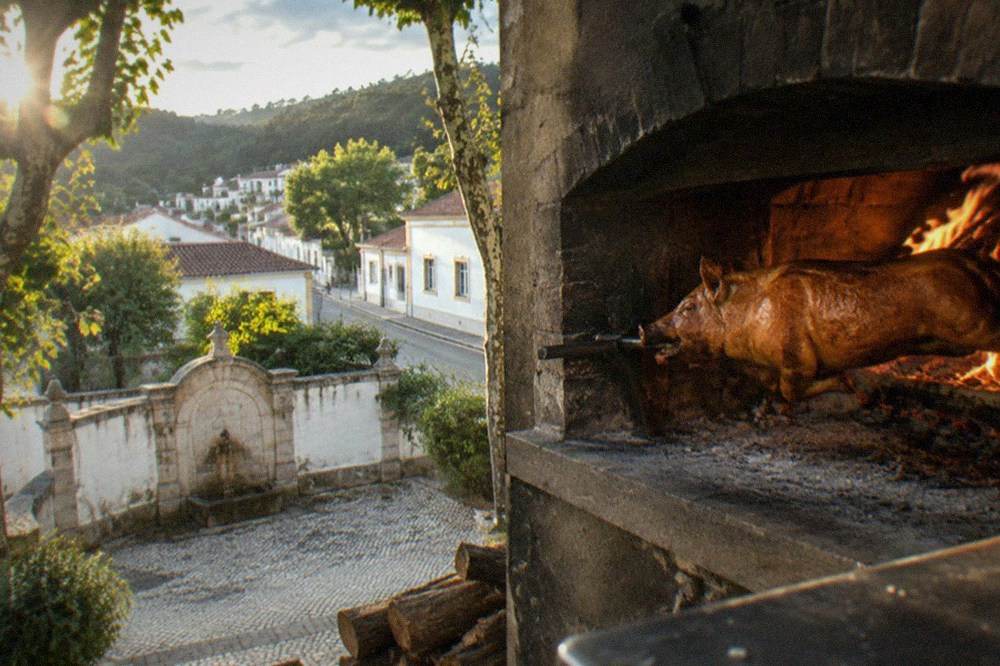 A wood-fired oven with a whole suckling pig roasting inside a Bairrada restaurant