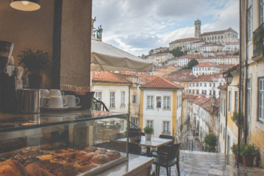 A Coimbra café counter with pastries and coffee cups in the morning