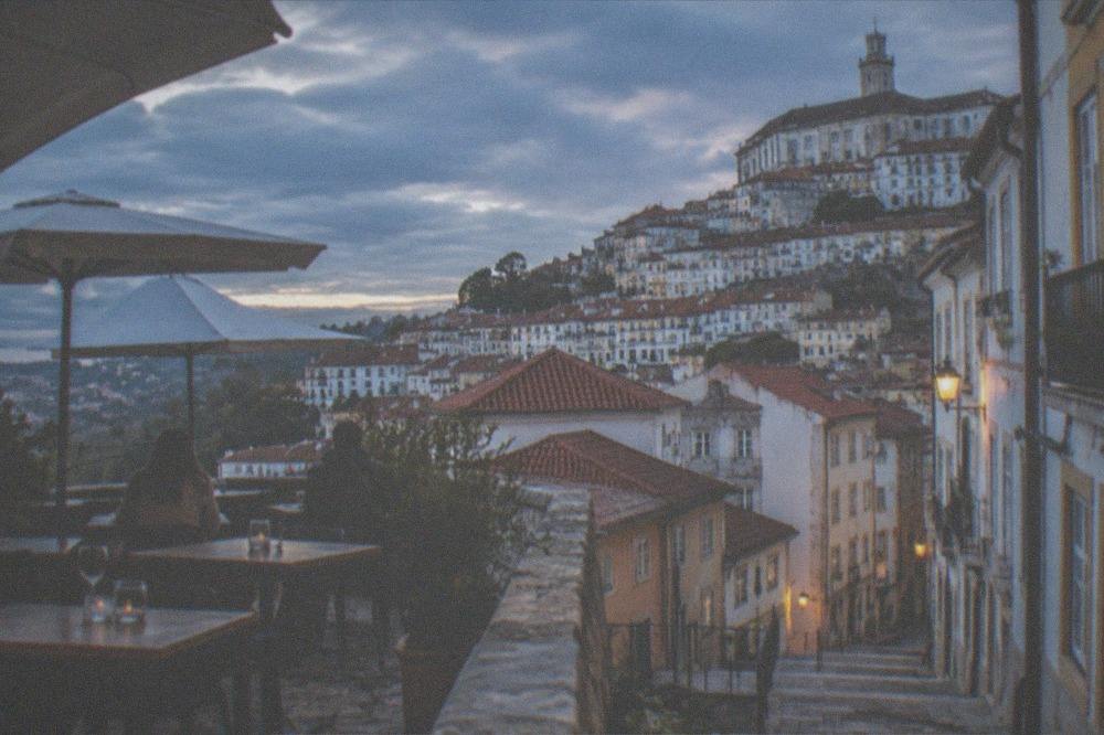An outdoor restaurant terrace in Coimbra with tables in evening sunlight