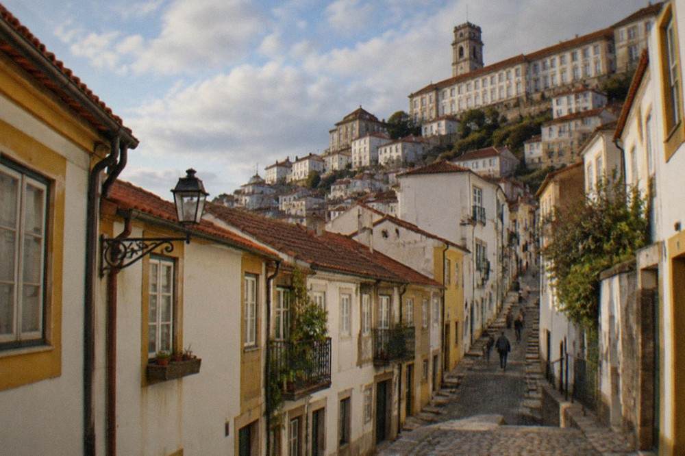 A steep cobbled street in Coimbra's old town rising toward the university buildings above