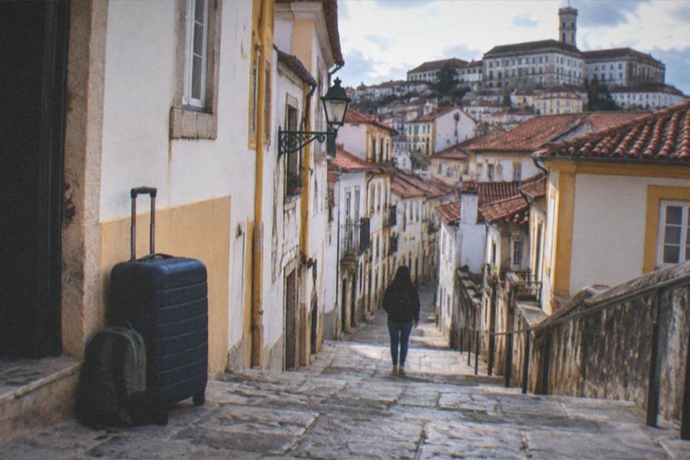 An overpacked large suitcase beside a small daypack on a hotel room floor