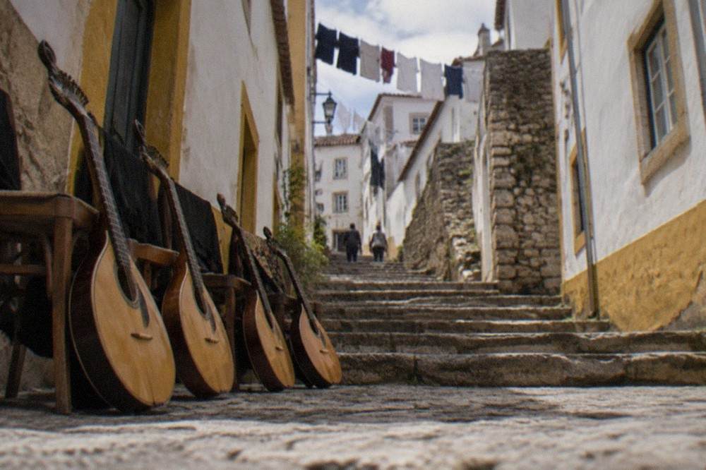 A row of Coimbra fado guitars resting against chairs before a performance