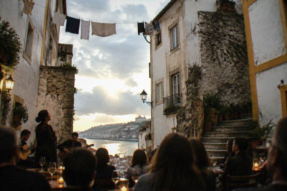 An audience seated at candlelit tables listening to a fado singer in a small Coimbra venue