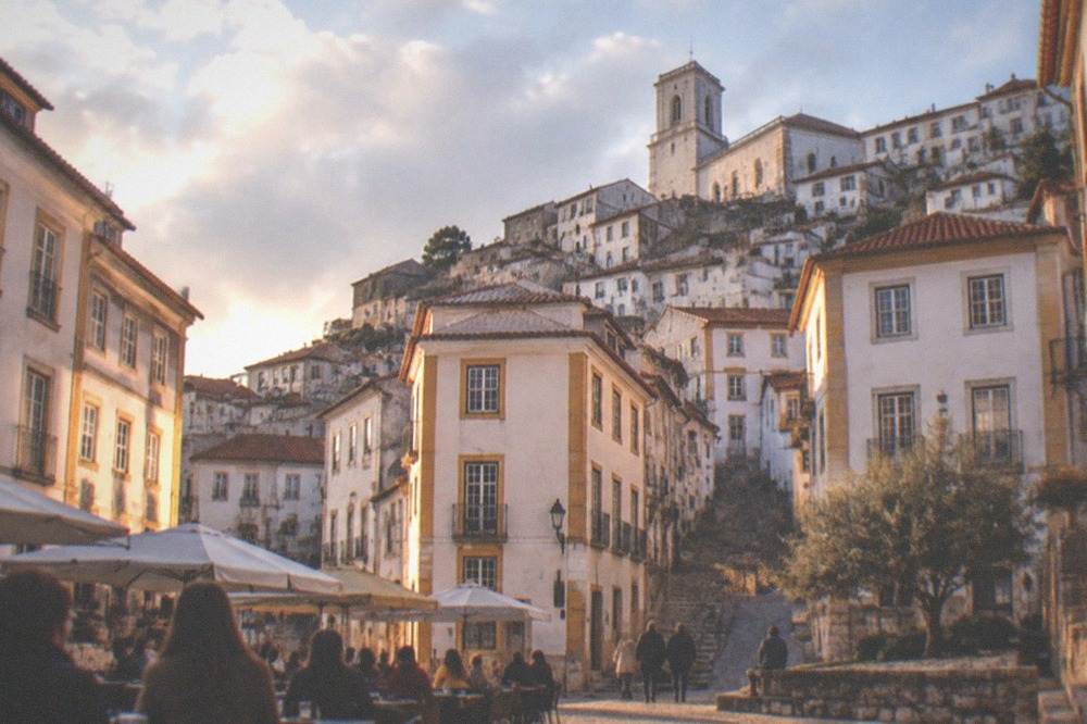 Cobbled square in Coimbra in warm evening light with people sitting outdoors