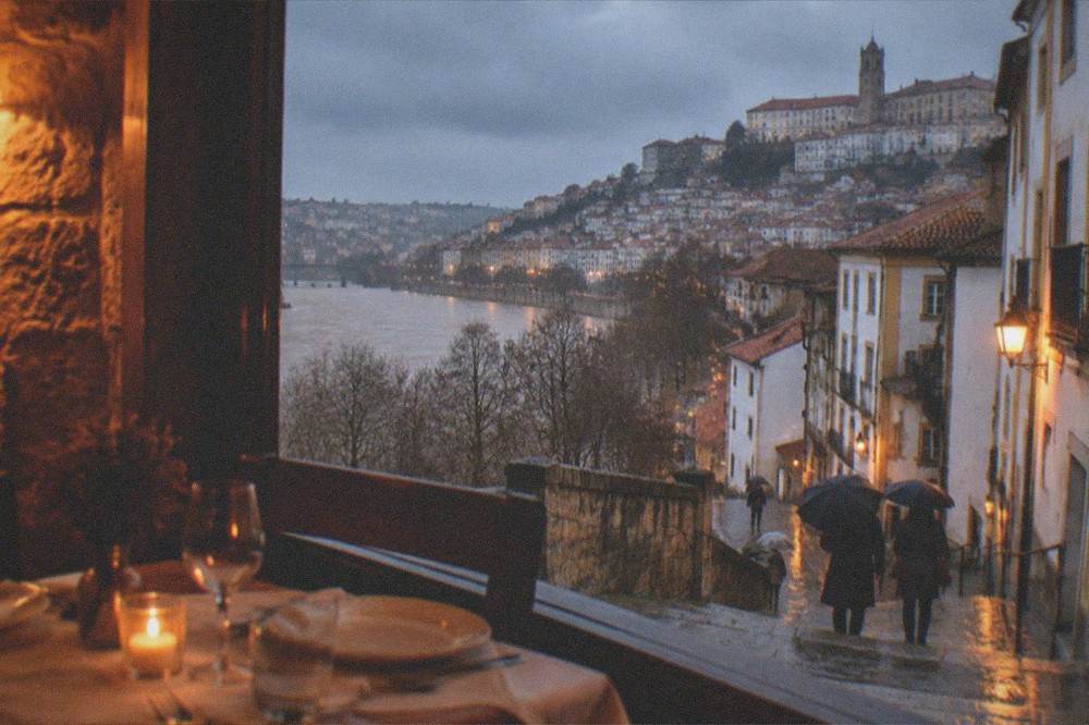 Warm lamplight in a small Coimbra restaurant with stone walls and a winter dinner table set