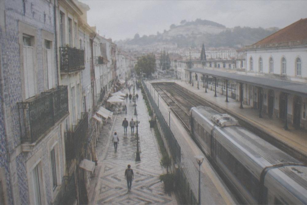 A train platform with a regional train waiting beside a station building