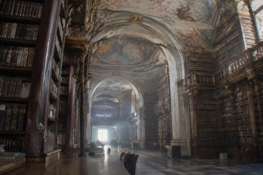 The baroque reading room of the Biblioteca Joanina with its painted ceiling and tall wooden bookshelves