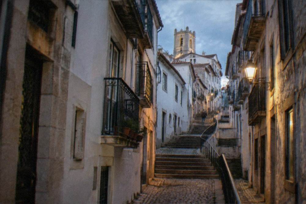 Narrow cobbled street in Coimbra's upper town with warm afternoon light on stone walls