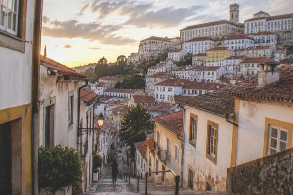 Evening light over Coimbra's rooftops with the university buildings rising above the old town.