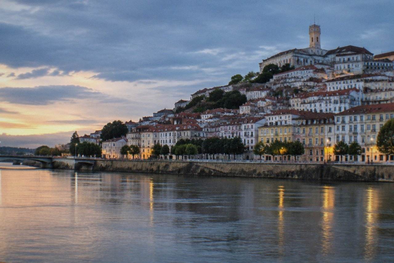 The hillside old town of Coimbra seen from across the River Mondego, with the university tower rising above tiled rooftops