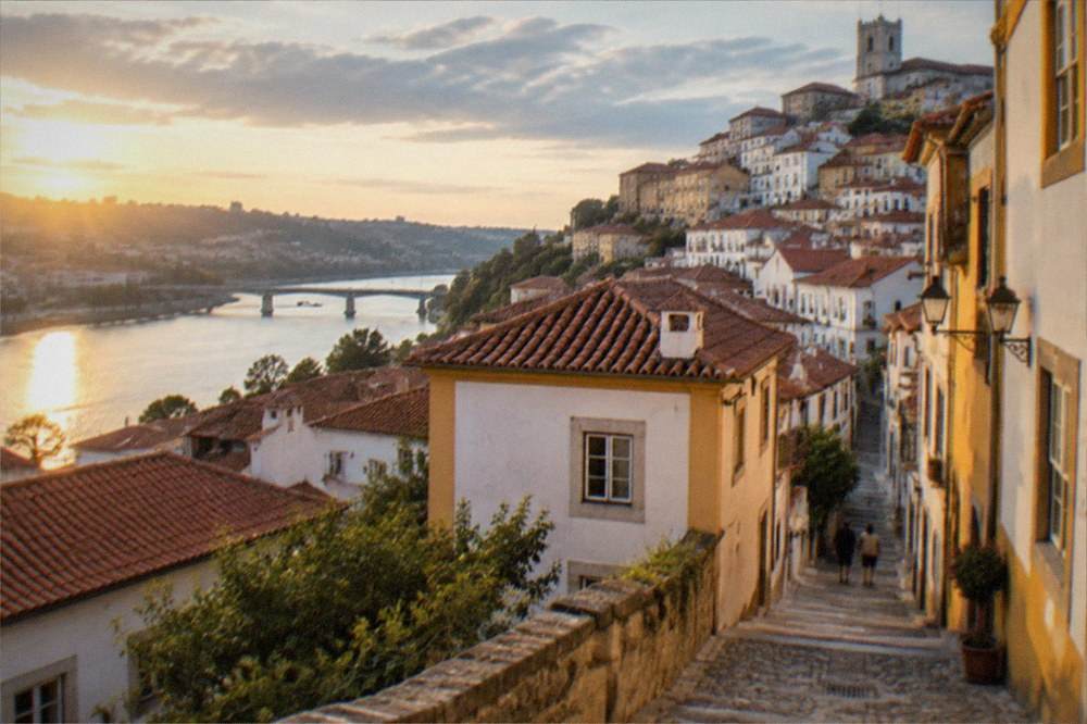 Warm evening light over the tiled roofs of Coimbra old town and the river below