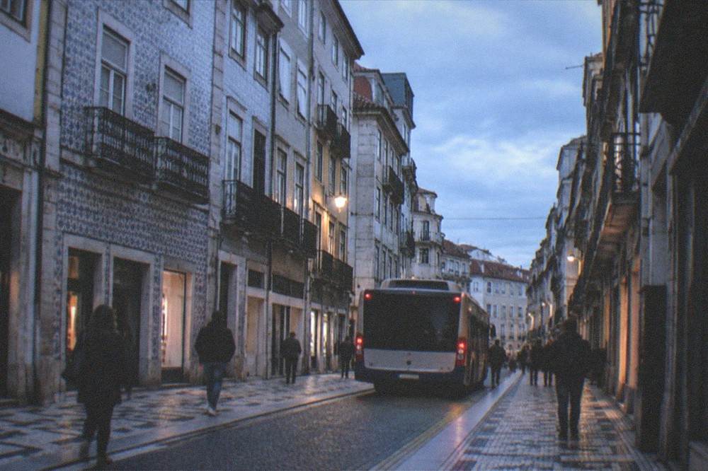 A bus and pedestrians on a street in the Baixa lower town of Coimbra