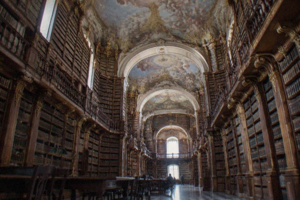 The grand baroque reading room of the Biblioteca Joanina with its painted ceiling and tall bookshelves