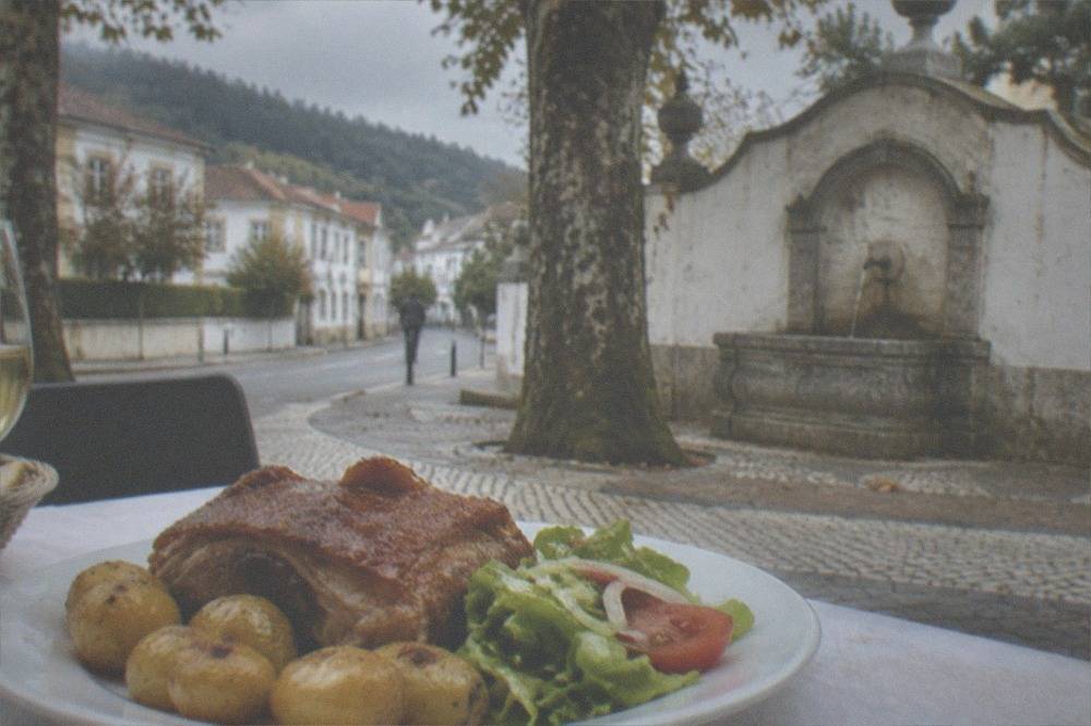 A plate of roast suckling pig with potatoes and salad on a restaurant table