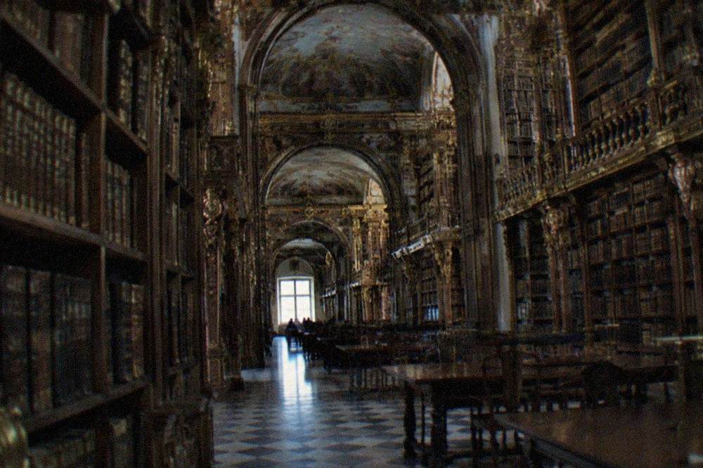 Interior of the baroque Joanina Library with tall ornate bookshelves and gilded decoration