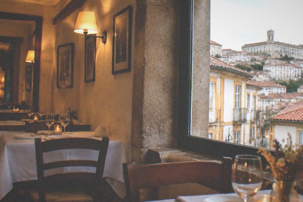 Cozy restaurant interior in Coimbra with warm lighting and set tables
