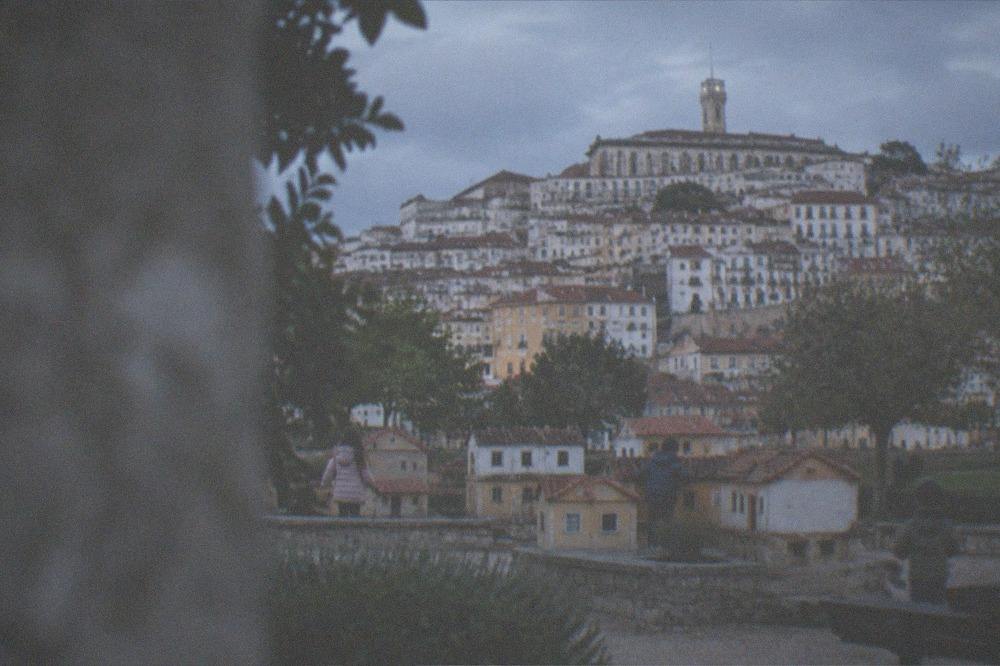 Children exploring miniature houses at an outdoor park in Coimbra under grey skies