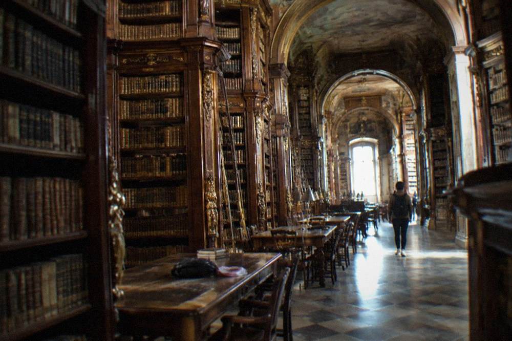 Grand baroque reading room inside the Joanina Library with dark wooden bookshelves