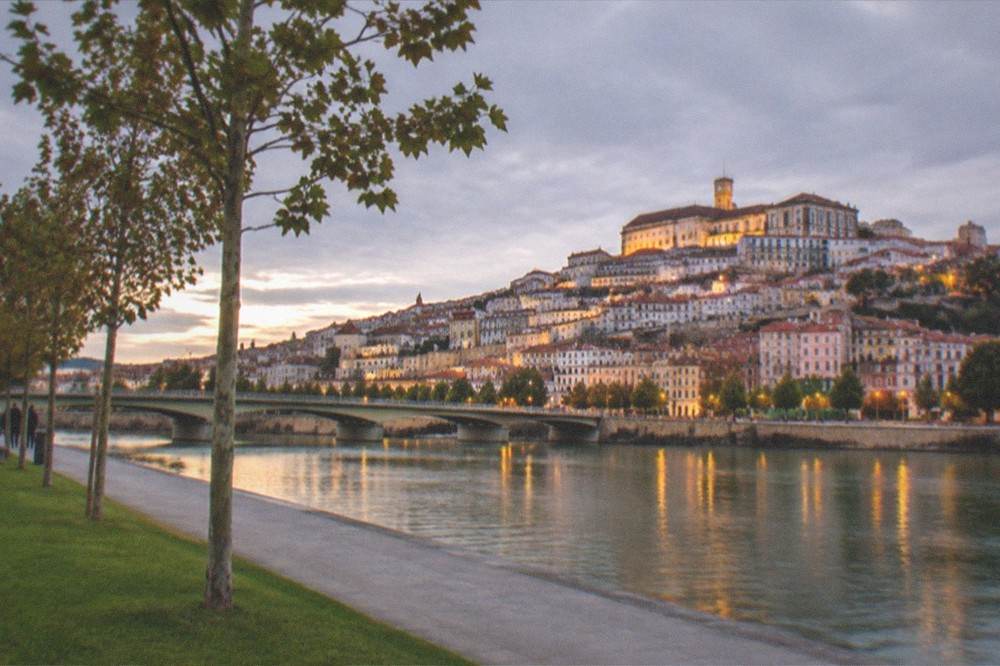 Evening view of Coimbra's illuminated old town from across the Mondego river