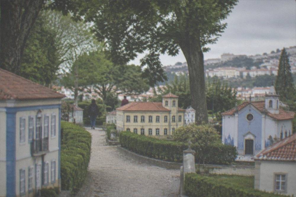Miniature Portuguese buildings at the Portugal dos Pequenitos park seen from a pathway.
