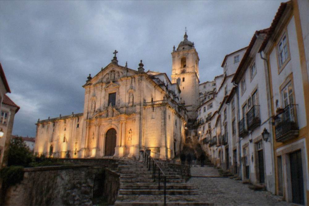 The illuminated facade of a monastery church in central Coimbra in the early evening.