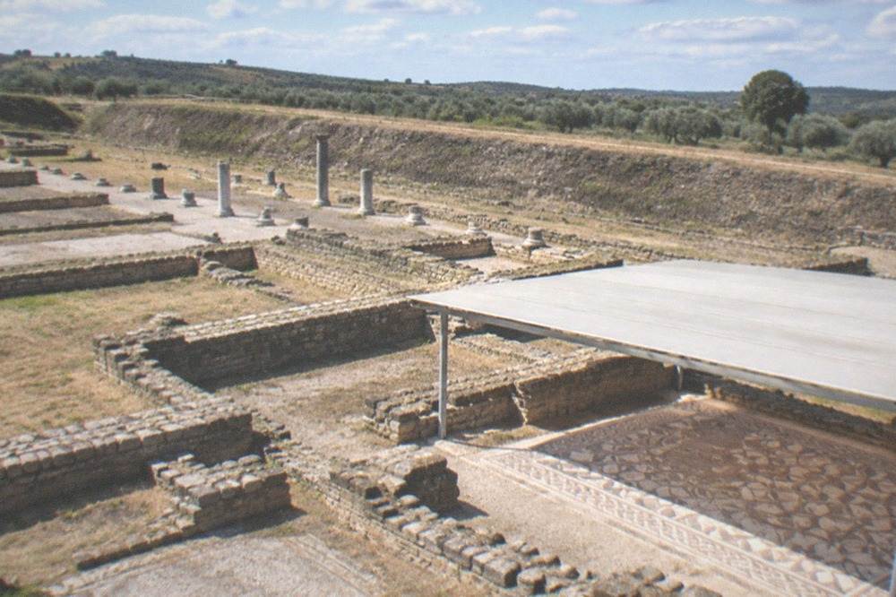 The Roman ruins of Conimbriga with column bases and mosaic floors under a clear sky