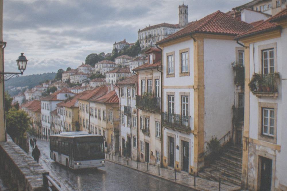 A city bus on a Coimbra street with the old town buildings behind it